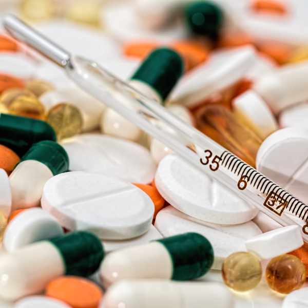a thermometer on top of a pile of tablets and capsules